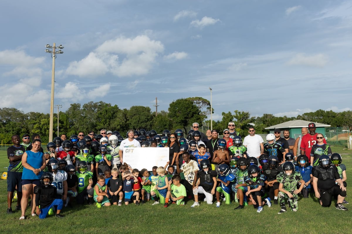 A CFY Pinellas County football team posing for a picture with their grant check on an outdoor field.