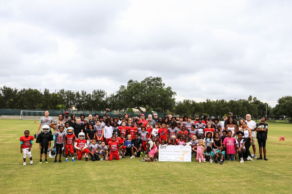 Youth football players from the Clearwater Jr. Tornadoes on the field in Clearwater, Florida., holding their grant check.
