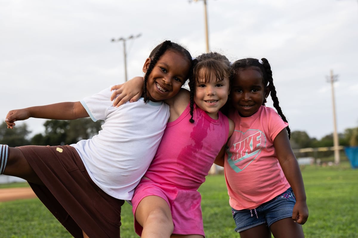 Seminole Seahawks youth cheerleaders hugging each other on the outdoor football field. 